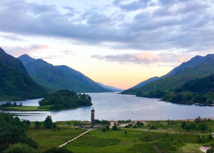 A sunrise above grassy flats, green mountains and a blue loch in the Scottish Highlands. Photo: Katia De Juan