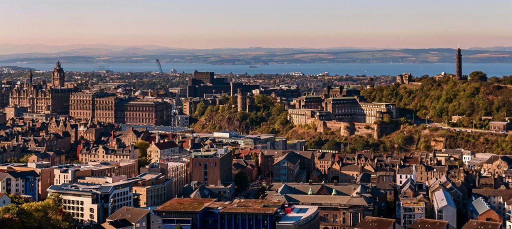 A city skyline, with a body of water and mountains in the distance