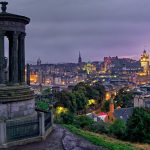 A stone monument on a hill, and city skyline.